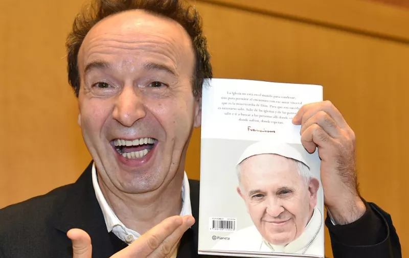 Italian actor/director Roberto Benigni smiles as he shows a copy of the pope Francis' interview book "The name of God is Mercy", during the presentation of the book at the Vatican on January 12, 2016. / AFP / ALBERTO PIZZOLI