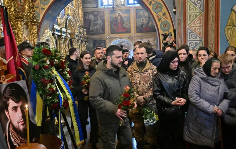 Finnish Prime Minister Sanna Marin (2ndL) and Ukrainian President Volodymyr Zelensky (C) hold flowers as they attend a memorial service for Dmytro Kotsiubailo, a Ukrainian serviceman known as "Da Vinci" killed in combat on the frontline in Bakhmut, at the Orthodox Saint Michael's Golden-Domed Monastery, in Kyiv on March 10, 2023, amid the Russian invasion of Ukraine. (Photo by Sergei SUPINSKY / AFP)