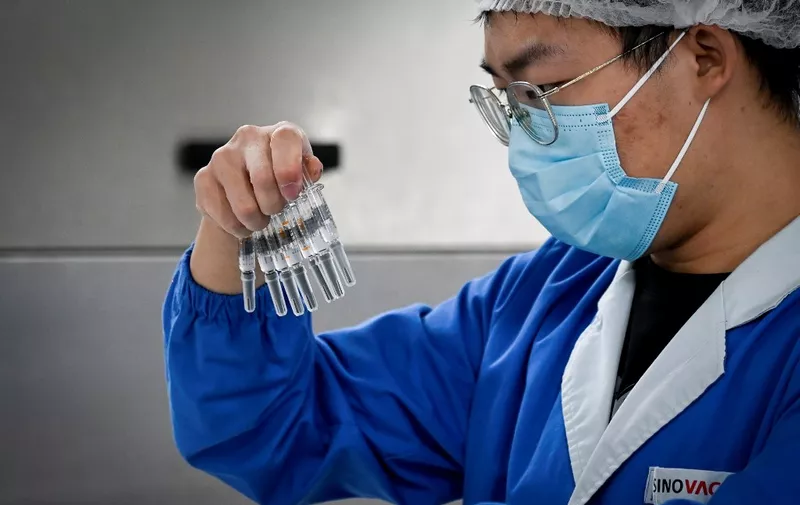 A staff member checks vaccines during a media tour of a new factory built to produce a COVID-19 coronavirus vaccine at Sinovac, one of 11 Chinese companies approved to carry out clinical trials of potential coronavirus vaccines, in Beijing on September 24, 2020. (Photo by WANG ZHAO / AFP)
