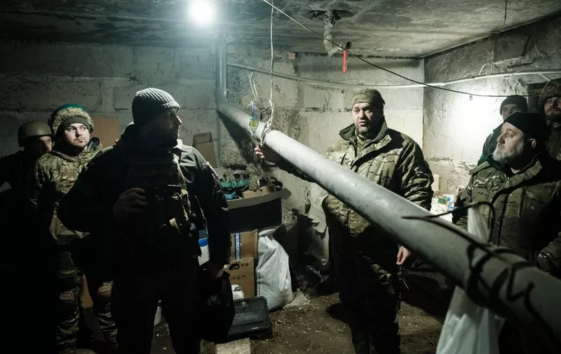 Ukrainian servicemen of the State Border Guard Service talk near the stove pipe in the shelter in Bakhmut on February 16, 2023, as the head of Russia's mercenary outfit Wagner said it could take months to capture the embattled Ukraine city and slammed Moscow's "monstrous bureaucracy" for slowing military gains. - Russia has been trying to encircle the battered industrial city and wrest it ahead of February 24, the first anniversary of what it terms its "special military operation" in Ukraine. (Photo by YASUYOSHI CHIBA / AFP)