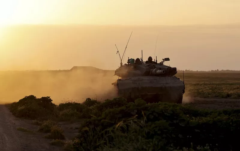 A picture taken from Israel near the border with the Gaza Strip on March 6, 2024 shows an Israeli army tank moving along the border area, as battles between Israel and the Palestinian militant group Hamas continue. (Photo by JACK GUEZ / AFP)