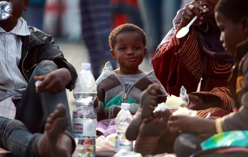 Migrants eat after disembarking from the Royal Navy ship HMS "Bulwark" upon their arrival in the port of Catania on the coast of Sicily on June 8, 2015. Italy's wealthy North vowed that it would refuse to accommodate any more migrants as thousands more were rescued in the Mediterranean by a multinational flotilla of ships. As another frantic weekend of rescues unfolded, nearly 6,000 people were plucked to safety from packed fishing boats and rubber dinghies off Libya. AFP PHOTO / GIOVANNI ISOLINO