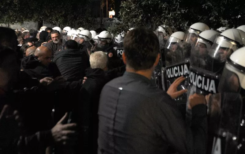 Montenegro's opposition protesters scuffle with police on October 17, 2015 in Podgorica. Montenegro's police used tear gas late Saturday to disperse a few hundred opposition protesters trying to rally here in front of the parliament despite a police ban. Several hundred officers sealed off key government institutions in downtown Podgorica preventing the protesters seeking resignation of Prime Minister Milo Djukanovic left-wing government, to approach the assembly.   AFP PHOTO / SAVO PRELEVIC