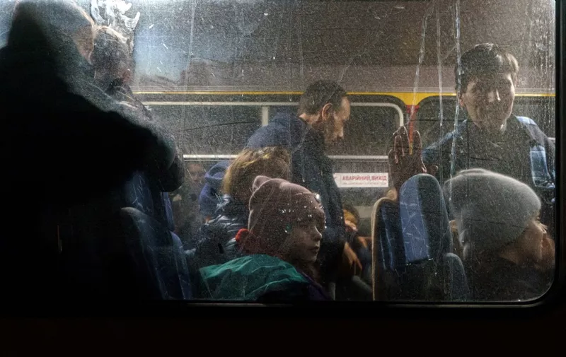 Passengers look through a bus window as a convoy of 30 buses carrying evacuees from Mariupol and Melitopol arrive at the registration center in Zaporizhzhia, on April 1, 2022. - Late on April 1, people who managed to flee Mariupol to Russian-occupied Berdiansk were from there carried on dozens of buses to Zaporizhzhia, some 200 kilometers (120 miles) to the northwest, according to an AFP reporter on the scene. (Photo by emre caylak / AFP)