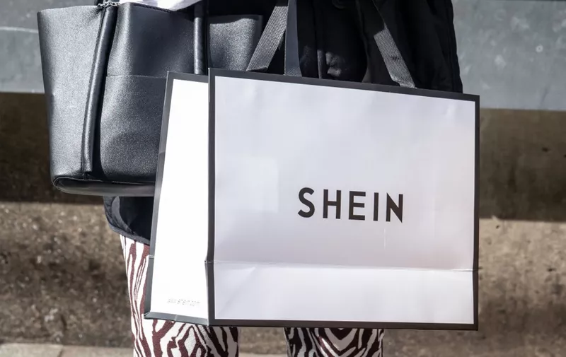 A woman holds a Shein shopping bag stand outside the first permanent showroom of Chinese online fast fashion giant Shein on the opening day of the shop in Tokyo on November 13, 2022. (Photo by Yuichi YAMAZAKI / AFP)