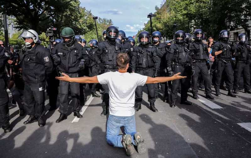 BERLIN, GERMANY - AUGUST 29: A demonstrators gestures in front of German rior police, as coronavirus skeptics and right-wing extremists march in protest against coronavirus-related restrictions and government policy on August 29, 2020 in Berlin, Germany. City authorities had banned the planned protest, citing the flouting of social distancing by participants in a similar march that drew at least 17,000 people a few weeks ago, but a court overturned the ban. (Photo by Omer Messinger/Getty Images)