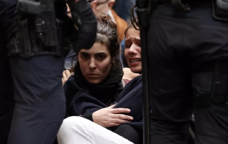 Two girls sit on the pavement after the arrival of Spanish police officers at a polling station in Barcelona, on October 1, 2017, on the day of a referendum on independence for Catalonia banned by Madrid.

More than 5.3 million Catalans are called today to vote in a referendum on independence, surrounded by uncertainty over the intention of Spanish institutions to prevent this plebiscite banned by justice.
 / AFP PHOTO / PAU BARRENA