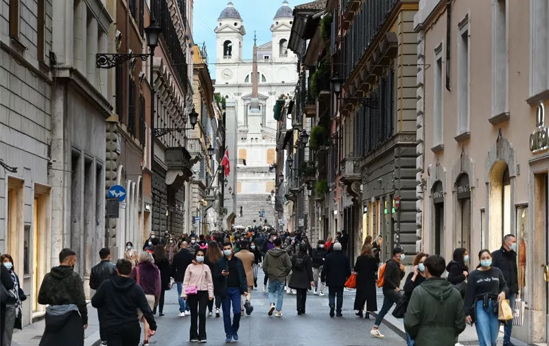 A general view shows people walk across the Via dei Condotti luxury shopping street, with the Trinita dei Monti church in background, in downtown Rome on November 14, 2020, during the Covid-19 pandemic caused by the novel coronavirus. - The Italian government imposed tighter restrictions on another five regions on November 10 as it tries to stem escalating new cases of coronavirus, while still resisting a nationwide lockdown. (Photo by Alberto PIZZOLI / AFP)