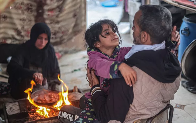 Members of the Rabaya family prepare a meal to break their fast amidst the rubble of their home, which was destroyed by an Israeli strike, during the Muslim holy month of Ramadan in Rafah on March 23, 2024, amid ongoing battles between Israel and the militant group Hamas. (Photo by SAID KHATIB / AFP)