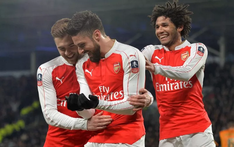 Arsenal's French striker Olivier Giroud (C) celebrates with Arsenal's English defender Calum Chambers (L) and Arsenal's Egyptian midfielder Mohamed Elneny after scoring the opening goal of the English FA cup fifth round replay football match between Hull City and Arsenal at the KC Stadium in Kingston upon Hull in north east England on March 8, 2016.  / AFP / Paul ELLIS / RESTRICTED TO EDITORIAL USE. No use with unauthorized audio, video, data, fixture lists, club/league logos or 'live' services. Online in-match use limited to 75 images, no video emulation. No use in betting, games or single club/league/player publications.  /