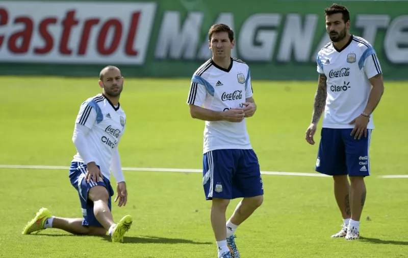 Argentina's forward Lionel Messi (C) gestures next to teammates midfielder Javier Mascherano (L) and forward Ezequiel Lavezzi (R) during a training session at "Cidade do Galo", in Vespasiano, near Belo Horizonte, some 470kms north of Rio de Janeiro on June 17, 2014, ahead of the 2014 FIFA World Cup Brazil Group F football match Argentina against Iran to be held at the Mineirao Stadium in Belo Horizonte on June 21.   AFP PHOTO / JUAN MABROMATA