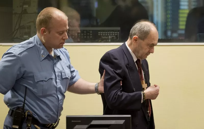 Bosnian Serb general Zdravko Tolimir (R) is escorted by a guard in the courtroom of UN's Yugoslav war crimes court in The Hague, on April 8, 2015. The UN's Yugoslav war crimes court found Bosnian Serb general Zdravko Tolimir guilty of genocide for his role in the 1995 Srebrenica massacre, Europe's worst atrocity since World War II, and sentenced him to life in jail. AFP PHOTO / POOL / PETER DEJONG / AFP / POOL / PETER DEJONG