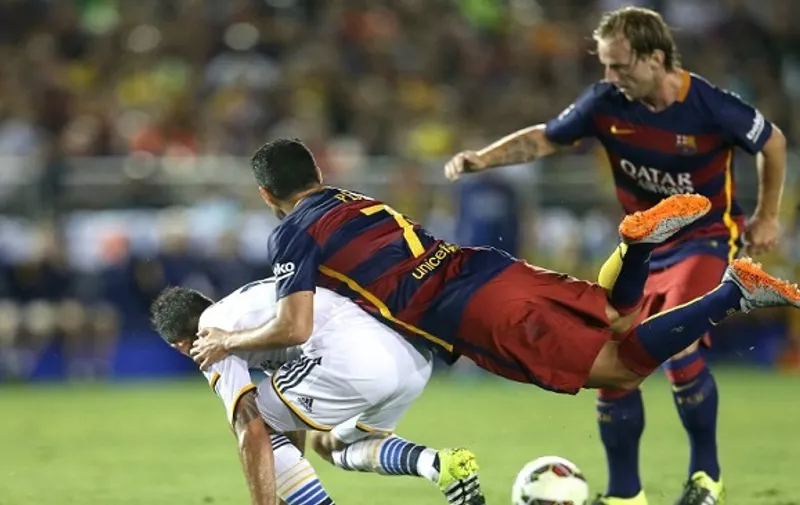 PASADENA, CA - JULY 21: Pedro Rodriguez #7 of FC Barcelona falls over Juninho #19 of the Los Angeles Galaxy as Ivan Rakitic #4 of Barcelona controls the ball in the International Champions Cup 2015 at Rose Bowl on July 21, 2015 in Pasadena, California.   Stephen Dunn/Getty Images/AFP