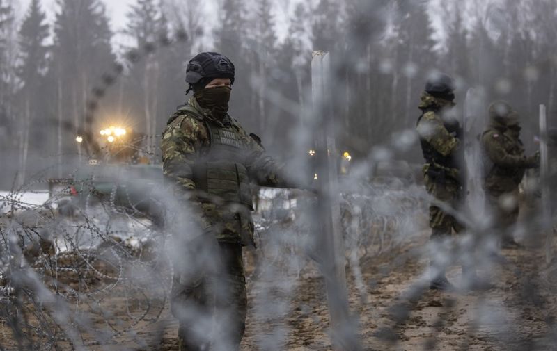 Border guard officers and soldiers are seen during the construction of a border wall along the Polish-Belarus border in Tolcze, Sokolka County, Podlaskie Voivodeship, in north-eastern Poland on January 27, 2022. - Polish contractors began work on a 353-million euro wall along the Belarus border aimed at deterring migrant crossings following a crisis in the area last year. The 5.5-metre high wall will run along 186 kilometres (115 miles) of the border -- almost half the total length -- and is to be completed in June. (Photo by Wojtek RADWANSKI / AFP)