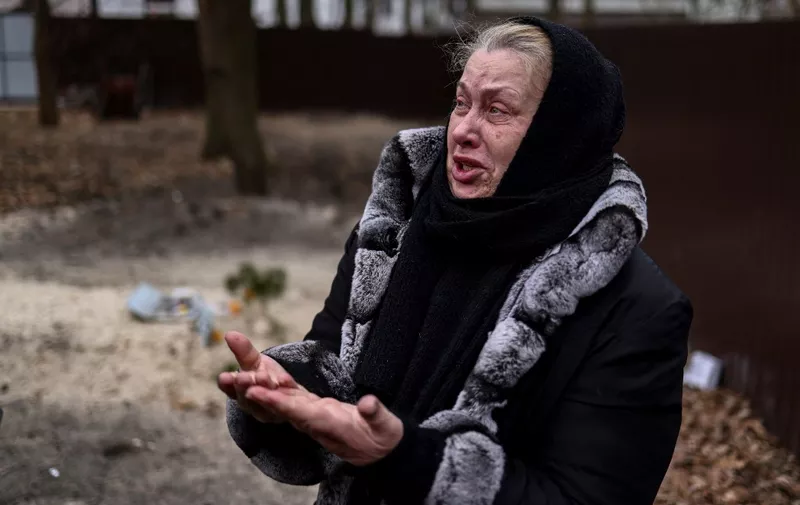 Bucha resident Tetiana Ustymenko weeps over the grave of her son, buried in the garden of her house, in Bucha, northwest of Kyiv, on April 6, 2022, during Russia's invasion launched on Ukraine. - Located 30 kilometres (19 miles) northwest of Kyiv's city centre, the town of Bucha was occupied by Russian forces on February 27 in the opening days of the war and remained under their control for a month. After the bombardments stopped, Ukrainian forces were able to retake the town on March 31. Large numbers of bodies of men in civilian clothing have since been found in the streets. (Photo by RONALDO SCHEMIDT / AFP)