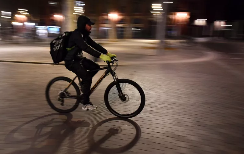 An Uber Eats food delivery cyclist crosses a deserted Place Saint Pierre in the city of Toulouse, on January 16, 2021 during the nationwide 18:00 overnight curfew restrictions taken to curb the spread of the Covid-19 pandemic. (Photo by GEORGES GOBET / AFP)