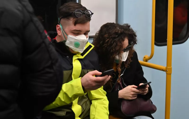 Commuters wearing protective respiratory mask are pictured in the underground subway in Milan on February 22, 2020. - An Italian man became the first European to die after being infected with the coronavirus on February 21, just hours after 10 towns in the country were locked down following a flurry of new cases. (Photo by ANDREAS SOLARO / AFP)