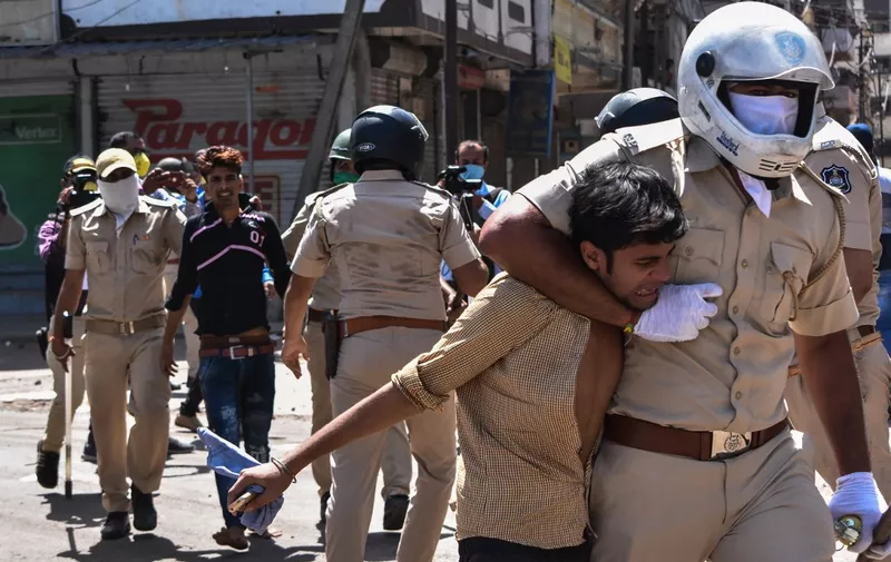 Gujarat police personnel detain stranded migrant workers during a protest demanding Gujarat's government travelling arrangements to return to their homes during nationwide lockdown as a preventive measure against COVID-19 coronavirus, in Surat, some 270 kms from Ahmedabad on May 4, 2020. (Photo by STR / AFP)
