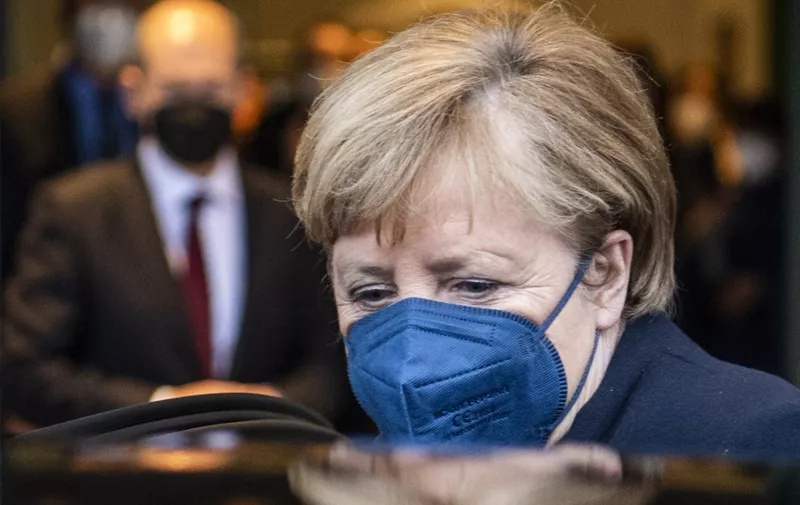 German Chancellor Olaf Scholz (background, L) looks on as his predecessor Angela Merkel gets into her car after she handed over the office to Scholz and leaves the Chancellery in Berlin on December 8, 2021. - Members of the parliament elected Olaf Scholz as the country's next Chancellor, ushering in a new political era with the centre-left in charge. Together with the Greens and the liberal Free Democrats, Scholz's SPD managed in a far shorter time than expected to forge a coalition that aspires to make Germany greener and fairer. (Photo by John MACDOUGALL / AFP)