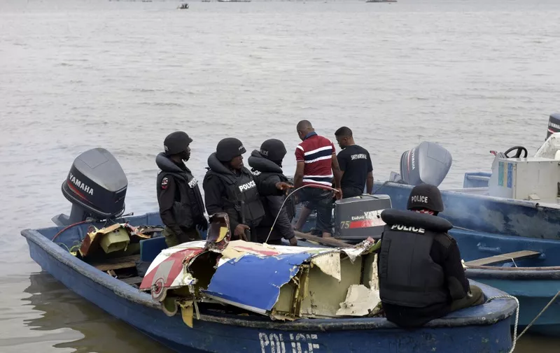 Marine police officers in a boat collect parts recovered from the helicopter, operated by the US-based Bristow Group, which crashed into a lagoon at the Oworonshoki district of Lagos on August 12, 2015.  At least four people were killed and six wounded when a helicopter plunged into a lagoon in Nigeria's commercial hub Lagos on August 12, emergency services said. The helicopter came down behind a police station in the Oworonshoki area in the city's north, according to the National Emergency Management Agency. Two people were still missing. AFP PHOTO / PIUS UTOMI EKPEI (Photo by PIUS UTOMI EKPEI / AFP)