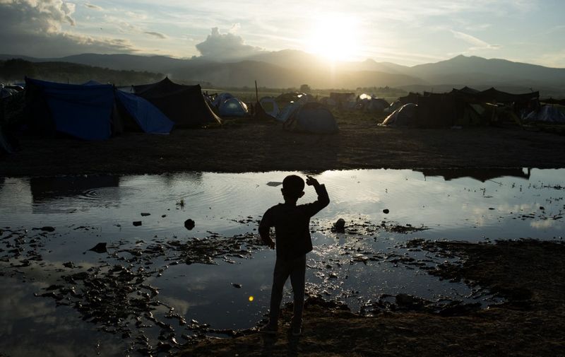 A boy throws stones into a puddle at a makeshift camp for migrants and refugees near the village of Idomeni not far from the Greek-Macedonian border on April 30, 2016. - Some 54,000 people, many of them fleeing the war in Syria, have been stranded on Greek territory since the closure of the migrant route through the Balkans in February. (Photo by TOBIAS SCHWARZ / AFP)