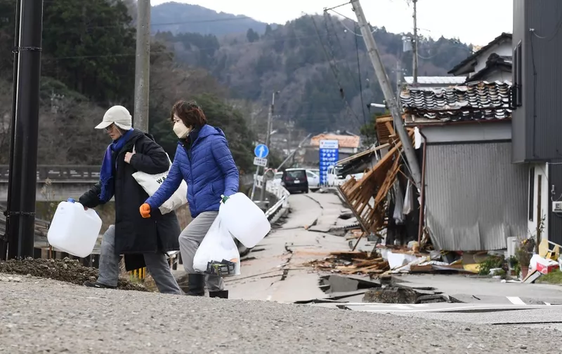 Residents carry water containers in the city of Wajima, Ishikawa prefecture, on January 5, 2024, after a major 7.5 magnitude earthquake struck the Noto region on New Year's Day. The death toll from a devastating earthquake in central Japan rose to 92 on January 5, regional authorities said, with the number of missing jumping to 242. (Photo by Toshifumi KITAMURA / AFP)
