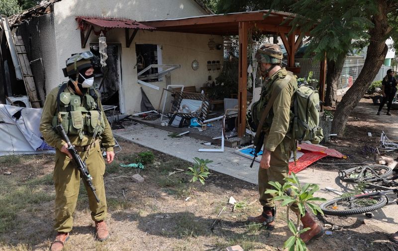 Israeli soldiers inspect the damage caused by rocket attacks from the Gaza Strip in the southern Israeli kibbutz of Kfar Aza on the border with the Palestinian territory, on October 10, 2023. Israel pounded Hamas targets in Gaza on October 10 and said the bodies of 1,500 Islamist militants were found in southern towns recaptured by the army in gruelling battles near the Palestinian enclave. (Photo by JACK GUEZ / AFP)