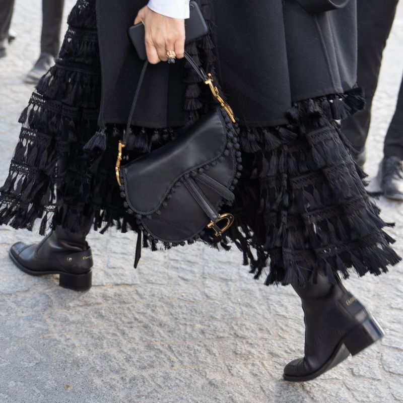 Detail of a black Dior bag with pompom trim, boots and tasseled skirt at the show.
Paris Fashion Week F/W 2023, Streetstyle, Paris, France - 10 Mar 2023,Image: 761919163, License: Rights-managed, Restrictions: , Model Release: no