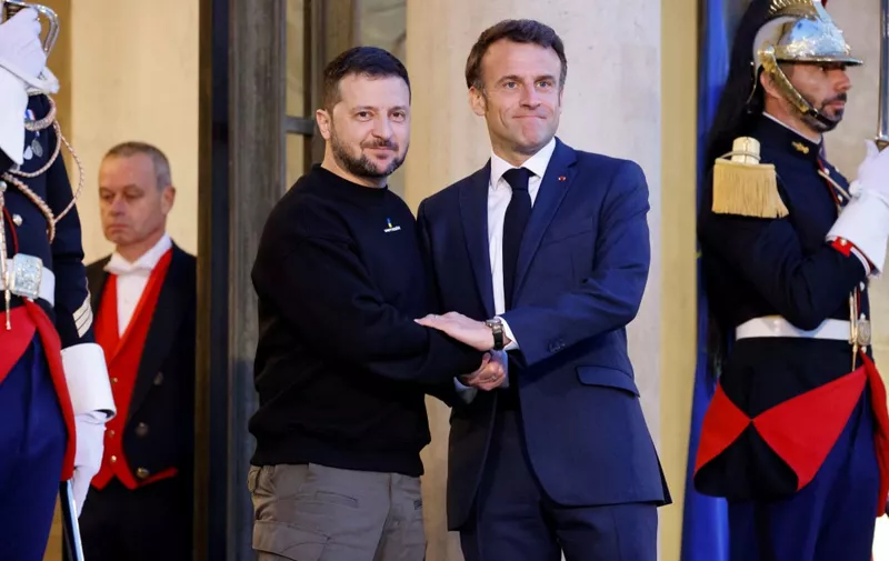 (FILES) Ukraine's President Volodymyr Zelensky (L) is welcomed by France's President Emmanuel Macron (c) upon his arrival at the Elysee presidential palace in Paris on May 14, 2023. French President Emmanuel Macron and Ukrainian leader Volodymyr Zelensky plan to sign a bilateral security agreement at the Elysee Palace on February 16, 2024, the French presidency said. (Photo by Ludovic MARIN / AFP)