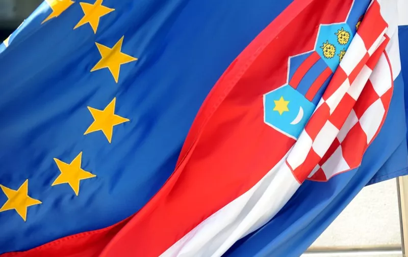 A picture taken on June 29, 2014 shows a Croatian (R) and a EU flag in front of the Ministry of Foreign Affairs in the center of Zagreb. One year ago, Croatia joined the European Union with great fanfare, sparking hopes that membership of the rich 28-nation bloc would transform the fortunes of the tourism-dependent economy.  Croatia remains one of the bloc's weakest economies, mired in a seemingly never-ending recession that has pushed unemployment to 20 percent -- half of the country's youth are without a job.AFP PHOTO/STRINGER