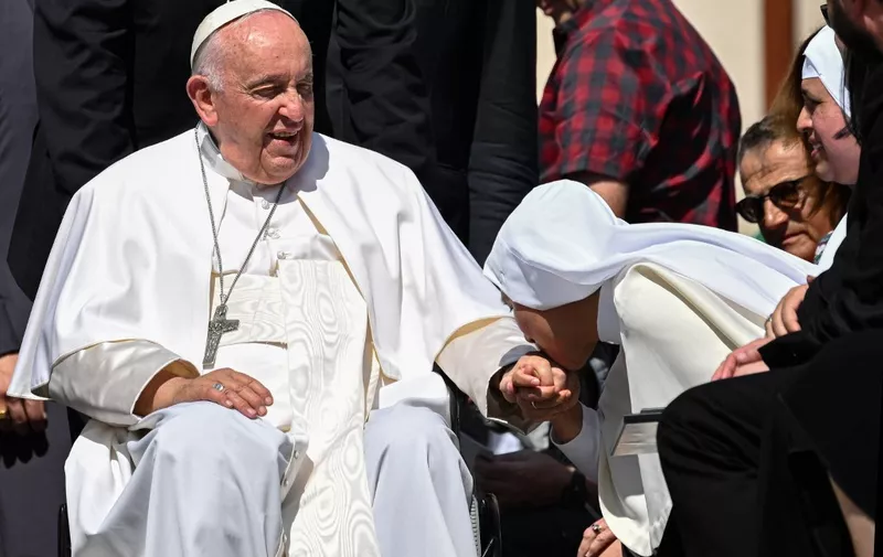 A nun kisses the hand of Pope Francis, seated in a wheelchair, at the end of the weekly general audience on June 7, 2023 at St. Peter's square as in The Vatican. (Photo by Andreas SOLARO / AFP)