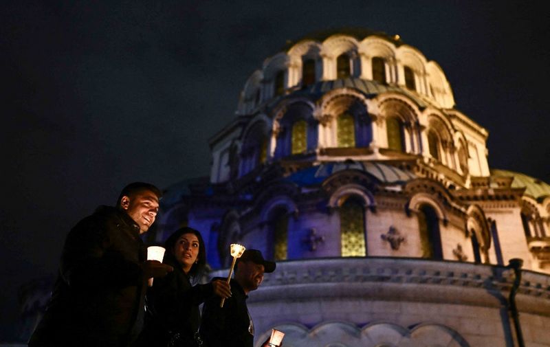 Bulgarian Orthodox worshippers walk holding candles during a midnight Easter mass in front of the golden-domed Alexander Nevski Cathedral in Sofia on April 14, 202. (Photo by Nikolay DOYCHINOV / AFP)