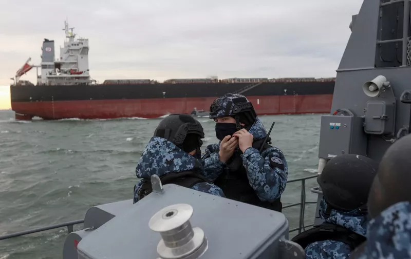 A servicemen of the Maritime Guard of the State Border Service of Ukraine adjusts his helmet during the inspection of a cargo ship for prohibited items and substances before entering a port in the northwestern part of the Black Sea, on 18 December 2023, amid the Russian invasion in Ukraine. This patrol is part of Kyiv's strategy aimed at keeping the Russian military fleet away from the Ukrainian coast, with the key mission of securing the corridor set up since August between Ukrainian ports in the Odessa region and the Bosphorus Strait, after Moscow slammed the door on an international grain agreement. (Photo by Anatolii Stepanov / AFP)