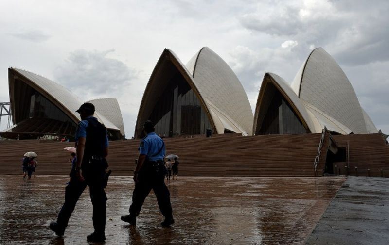 Police officers patrol in front of the Sydney Opera House in Sydney on January 14, 2016, after it was cordoned off in a security scare sparked by "information on social media" with people cleared from the harbour front precinct before police declared it safe. Metal barriers were erected with onlookers kept about 150 metres (500 feet) away from the building, with police officers and security personnel guarding the area in a 90-minute lockdown.  AFP PHOTO / Saeed KHAN / AFP / SAEED KHAN