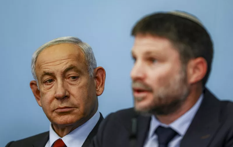 (L to R) Israeli Prime Minister Benjamin Netanyahu looks on as Finance Minister Bezalel Smotrich speaks during a press conference at the Prime Minister's office in Jerusalem on January 25, 2023. (Photo by RONEN ZVULUN / POOL / AFP)