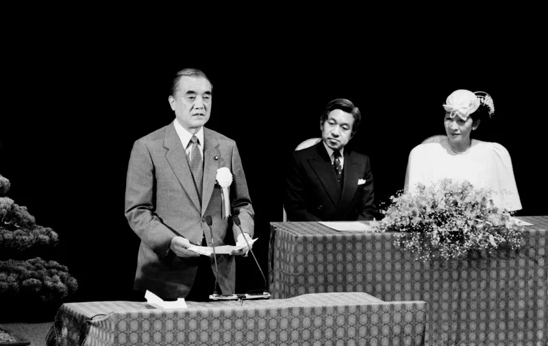 (FILES) This file photo taken on November 28, 1986 shows then-Japanese prime minister Yasuhiro Nakasone (L), flanked by then-Crown Prince Akihito (C) and Princess Michiko, delivering a congratulatory address at a ceremony in Tokyo marking the 30th anniversary of Japan's admission to the United Nations. - Nakasone, an ardent conservative who worked to forge a stronger military alliance with the United States, has died at the age of 101, local media said on November 29, 2019. (Photo by Ryosuke KAGIWADA / AFP)
