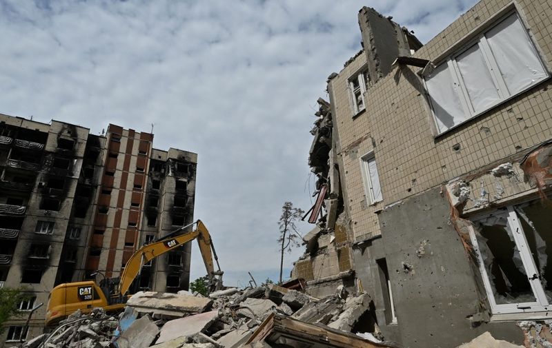 Workers dismantle a heavily damaged residential building in Irpin, on May 4, 2023, amid the Russian invasion of Ukraine. (Photo by Genya SAVILOV / AFP)