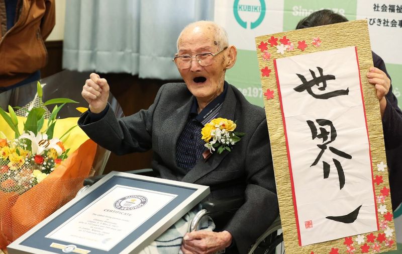 (FILES) In this Japan Pool picture received via Jiji Press on February 12, 2020, 112-year-old Japanese man Chitetsu Watanabe poses next to calligraphy reading in Japanese 'World Number One' after he was awarded as the world's oldest living male in Joetsu, Niigata prefecture. - A Japanese man recently named the world's oldest living male has died aged 112, a local official said on February 25, 2020. (Photo by JAPAN POOL / JIJI PRESS / AFP) / Japan OUT