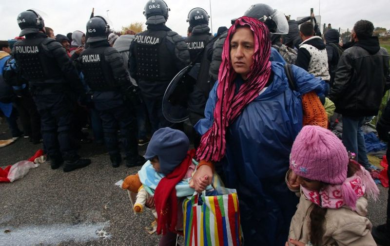 A woman holds  children by their hands as migrants and refugees cross the Croatia-Slovenia border on October 19, 2015 in Trnovec. Slovenian authorities said on October 19 they had refused to let in more than 1,000 migrants arriving from Croatia after a daily quota had been reached, stoking fears of a new human bottleneck on the western Balkan route. AFP PHOTO