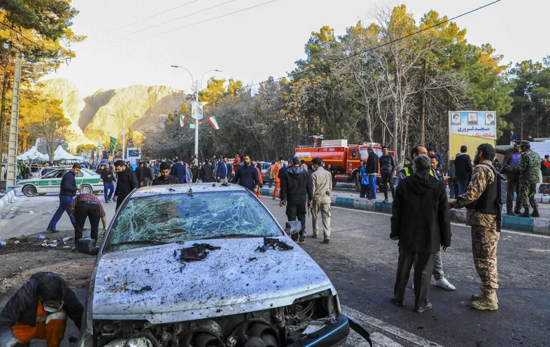 This picture shows people and Iranian emergency personnel at the site where two explosions in quick succession struck a crowd marking the anniversary of the 2020 killing of Guards general Qasem Soleimani, near the Saheb al-Zaman Mosque in the southern Iranian city of Kerman on January 3, 2024. Iran's president Ebrahim Raisi condemned on January 3 twin blasts that killed at least 103 people in the country's south where crowds gathered to mark the killing of general Qasem Soleimani. (Photo by Sare Tajalli / ISNA / AFP)