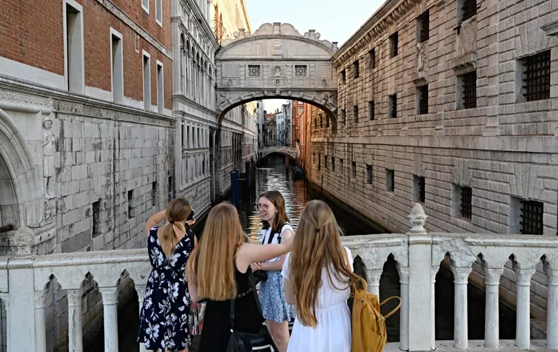 Tourists stand in front of Ponte dei Sospiri during the G20 finance ministers and central bankers meeting in Venice, on July  10 2021. G20 finance ministers gathered on July 9, 2021 in Venice under tight security, with global tax reform at the top of the agenda as the world's biggest economies seek to ensure multinational companies pay their fair share. (Photo by ANDREAS SOLARO / AFP)