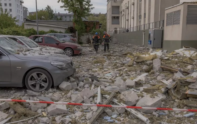 Emergency workers walk among debris in front of a residential building damaged as a result of a missile attack in Kharkiv, on May 14, 2024, amid the Russian invasion of Ukraine. (Photo by Roman PILIPEY / AFP)