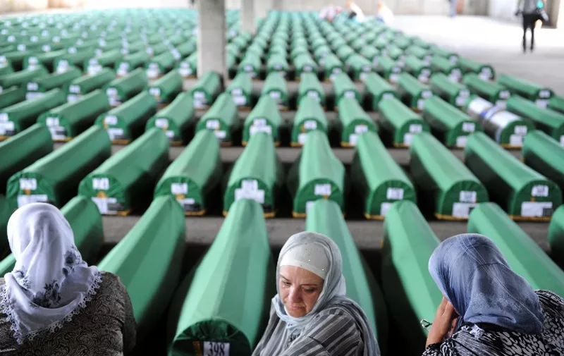 Bosnian muslim women cry and pray among 520 caskets stocked in an abandoned factory hangar, in preparation for a mass burrial ceremony at the Srebrenica Memorial Cemetary, in Potocari on July 10, 2012. Tens of thousands of people are expected in Potocari on July 11 to commemorate the 17th anniversary of the moment the UN-protected enclave fell to Bosnian Serb troops. The remains of 520 people will be buried alongside the 5,137 victims of the massacre already buried in the vast cemetery which faces the former UN army base. Some 8,000 Muslim men and boys were killed in just a few days after the eastern town under UN protection was captured by Bosnian Serb forces 17 years ago. AFP PHOTO / ELVIS BARUKCIC