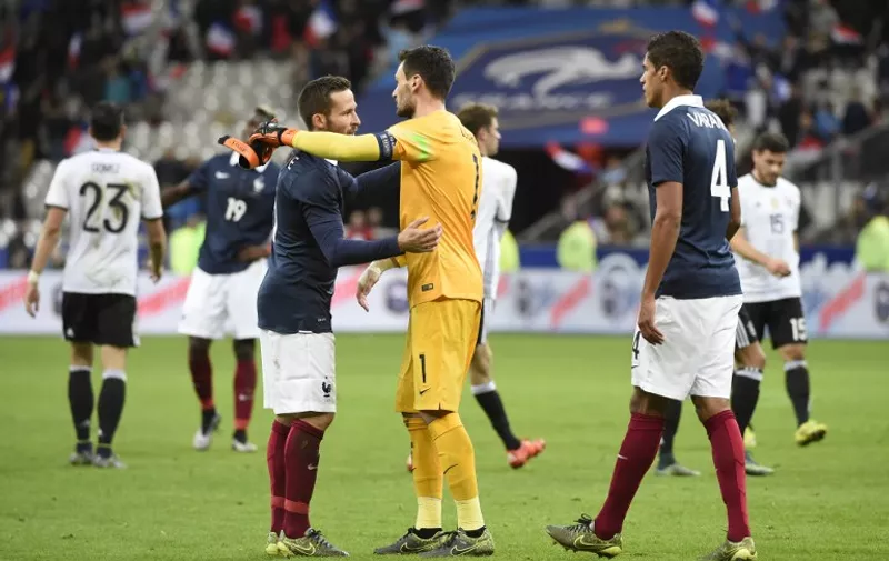 French midfielder Yohan Cabaye (L) embraces French goalkeeper and captain Hugo Lloris (C) as French defender Raphael Varane (R) looks on after France defeated Germany 2-0 in a friendly international football ahead of the Euro 2016, on November 13, 2015 at the Stade de France stadium in Saint-Denis, north of Paris.    AFP PHOTO / MIGUEL MEDINA