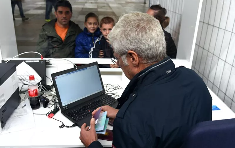 Martin Fuchs (R) checks the identification papers of the Bakari family from Albania at the central registration office for refugees in Greven, western Germany, on September 22, 2015. By establishing this institution, the government of the western federal state of North Rhine-Westphalia intends to reduce the burden of the reception facilities. They will only assist in the registration of refugees who will be subsequently taken back to their respective shelters across the state.     AFP PHOTO / PATRIK STOLLARZ