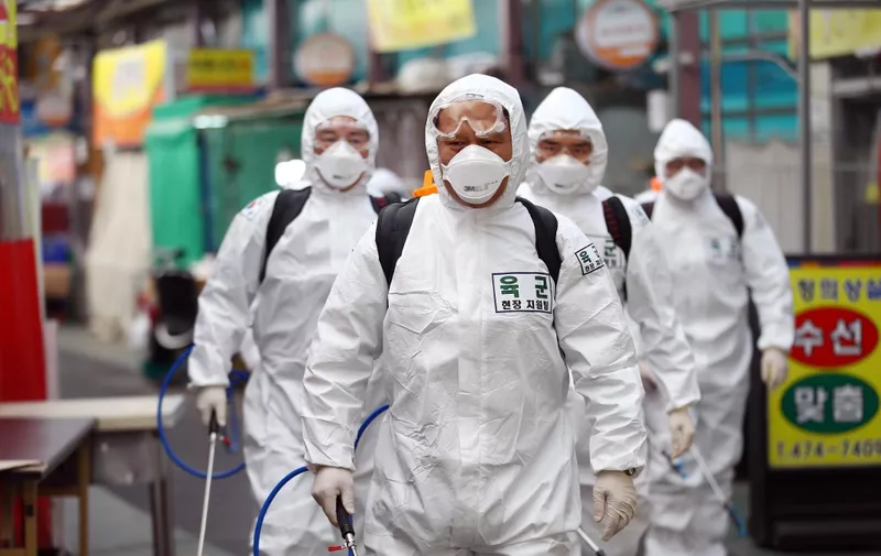 South Korean soldiers wearing protective gear spray disinfectant as part of preventive measures against the spread of the COVID-19 coronavirus, at a market in Daegu on March 2, 2020. - South Korea reported nearly 500 new coronavirus cases on March 2, sending the largest national total in the world outside China past 4,000. (Photo by - / YONHAP / AFP) / - South Korea OUT / REPUBLIC OF KOREA OUT  NO ARCHIVES  RESTRICTED TO SUBSCRIPTION USE