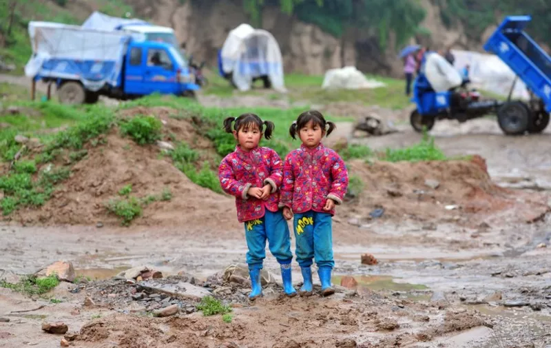 This picture taken on July 25, 2013 shows two twin sisters outside temporary tents in an earthquake-hit area of Minxian county in Dingxi, northwest China's Gansu province. At least 94 people were killed in the earthquake, China's official news agency reported, citing local authorities, with 1,000 more injured and 51,800 homes collapsed. CHINA OUT     AFP PHOTO / AFP / STR