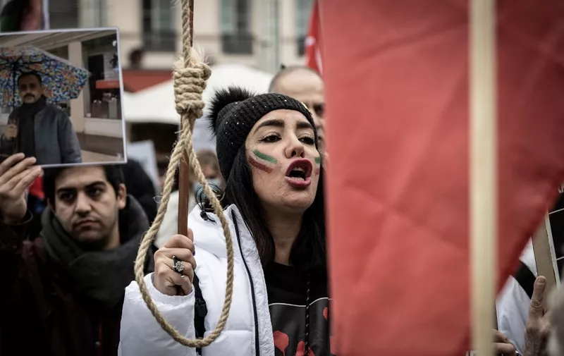 A woman holds a gallows rope during a rally in Lyon on January 8, 2023 against the Iranian regime, marking third anniversary of the downing of Ukrainian passenger jet, flight PS752 by Iranian forces shortly after it's takeoff from Tehran and to pay tribute to Mohammad Moradi, an Iranian student who committed suicide by drowning himself in the Rhone River in December 2022 to draw attention to the situation in Iran. (Photo by JEAN-PHILIPPE KSIAZEK / AFP)