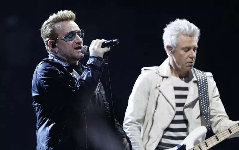 Irish band U2 singer Bono (L) performs on stage at the Bercy Accordhotels Arena in Paris on December 6, 2015.  / AFP / THOMAS SAMSON