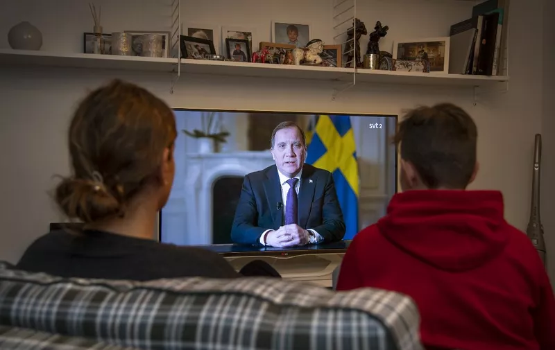 People in Stockholm watch Sweden's Prime Minister Stefan Lofven address the nation on new coronavirus COVID-19 crisis broadcast on Swedish national public television, SVT, on March 22, 2020. (Photo by Anders WIKLUND / various sources / AFP) / Sweden OUT